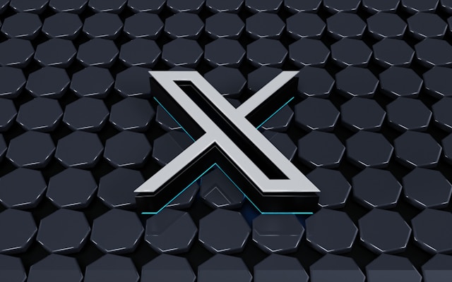 A sleek metallic "X" logo on a dark, hexagonal-patterned background.