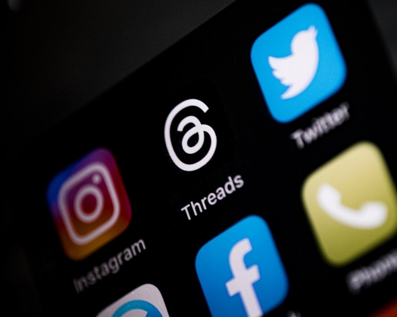 A close-up of a smartphone screen showing the Threads and Twitter app icons.