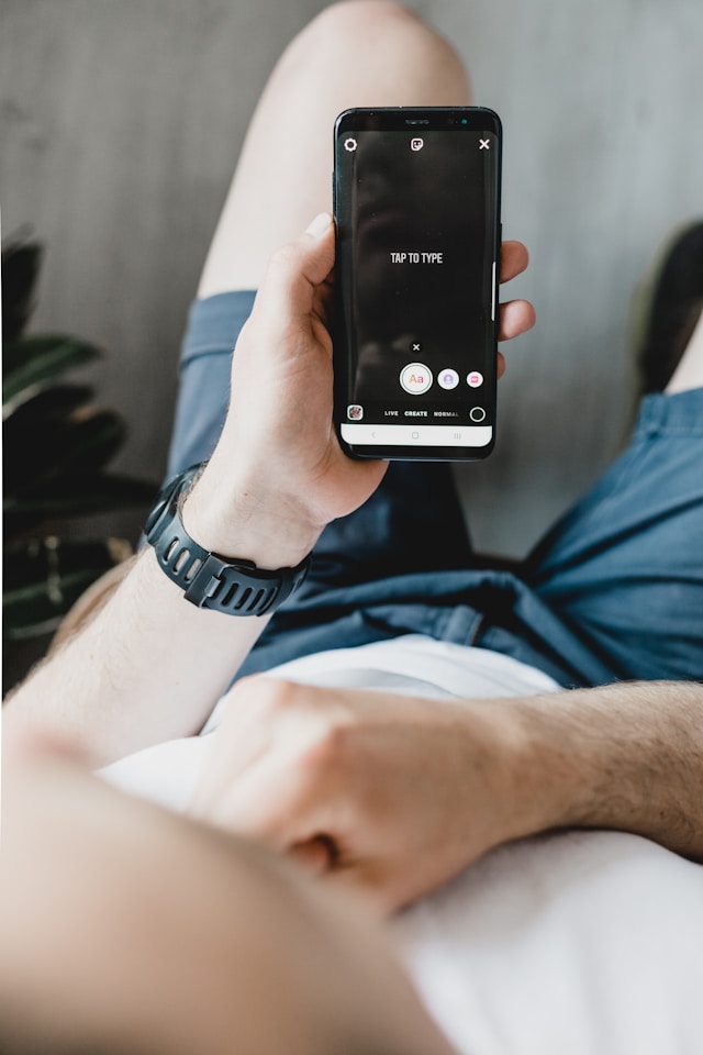 A person holding a smartphone, displaying a screen with the text "TAP TO TYPE" to create an Instagram story.