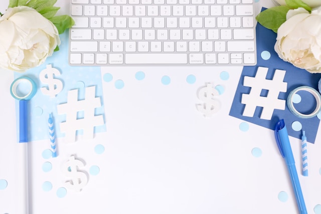 A flat lay with a keyboard, hashtags, dollar signs, and blue accents, representing social media strategy and monetization.